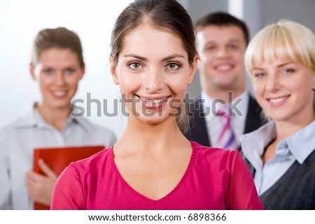 Portrait of confident woman in pink blouse on the background of her business team