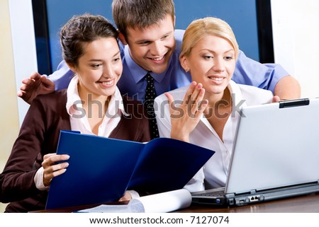 Business team of three people looking at monitor of laptop