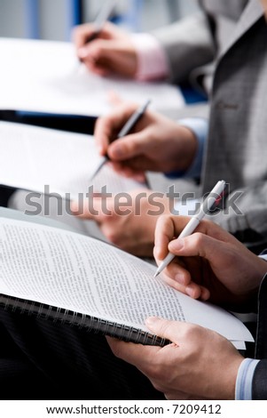 Image of human hands holding the pens and notepads with papers