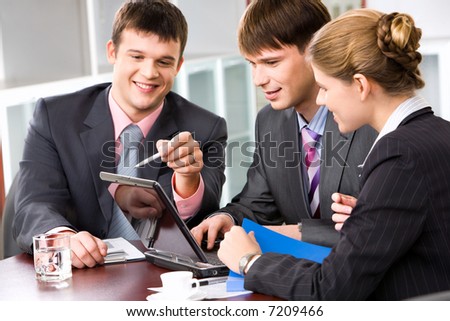 Confident manager is explaining the correct way of analysis to his colleagues in  the office pointing at the monitor