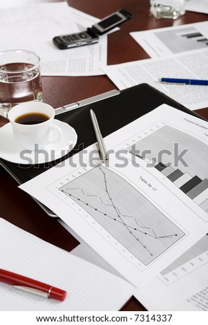 Image of documents, pens, folder, glass, cup and mobile on a table