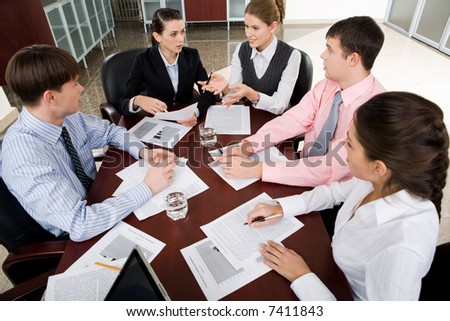 Photo of businesspeople gathered around the table discussing a new ideas