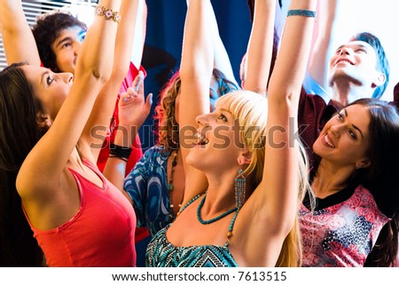 Happy young people lift up the hands at a party