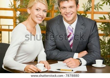Portrait of business woman and man looking at camera in a cafe