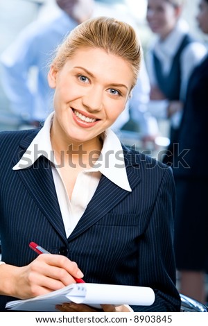 Portrait of strong secretary looking at camera during writing of text