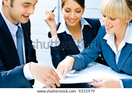 Business woman demonstrating her plan of work to co-workers pointing at a document