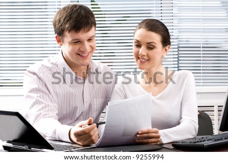 Image of two confident people reading a document together in the office