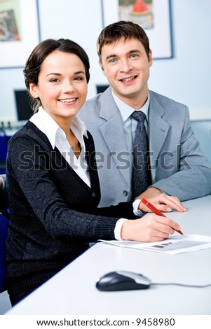 Portrait of two successful students sitting at the desk in the computer room and smiling