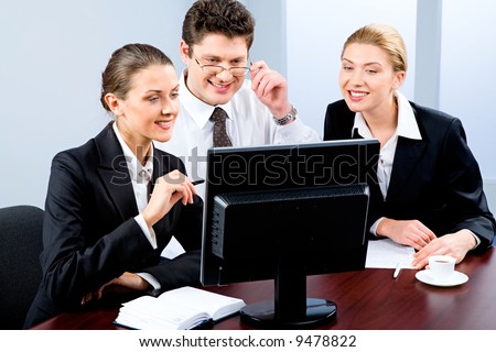 Portrait of three young specialists looking at monitor of computer