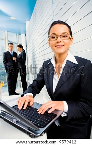 Successful woman doing some computer work on the background of business people in the office