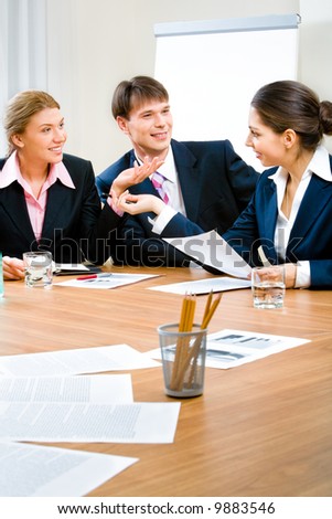 Image of three business people sitting at the table and discussing a new plan