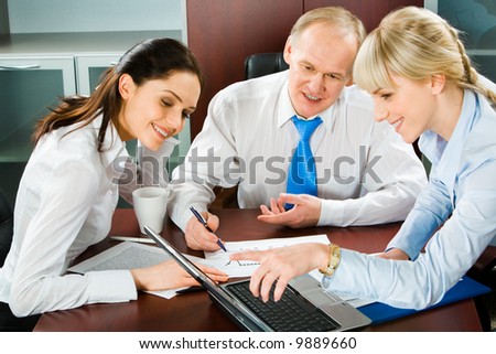 Portrait of sitting businesspeople looking into the screen of a laptop during business meeting