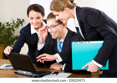 Photo of business woman explaining a computer work to her colleagues pointing at the laptop