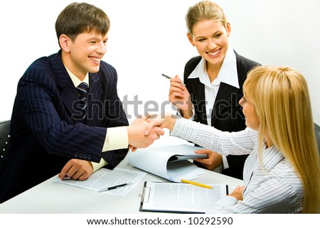 Portrait of two happy business partners shaking hands during business meeting with attractive smiling secretary sitting near by