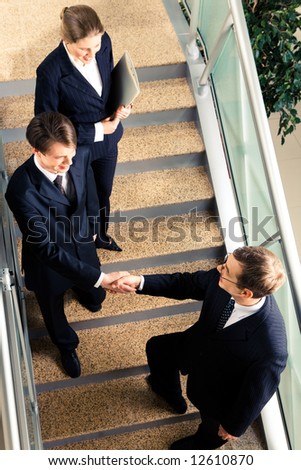View of handshake of business partners met on the stairs in the office building