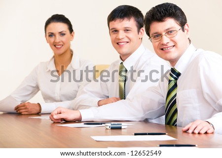 Portrait of confident business people sitting at the table and looking at camera with their boss at the front