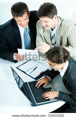 Vertical image of two businessmen discussing plan while woman typing document on the laptop