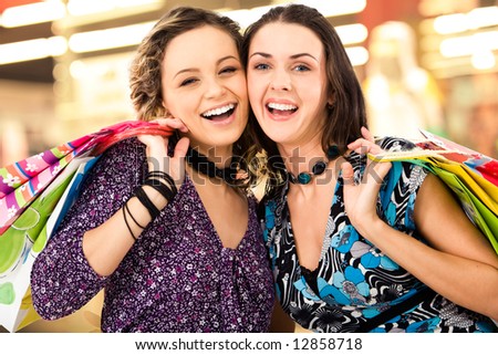 Faces of cheerful ladies in the shopping mall looking at camera amd laughing