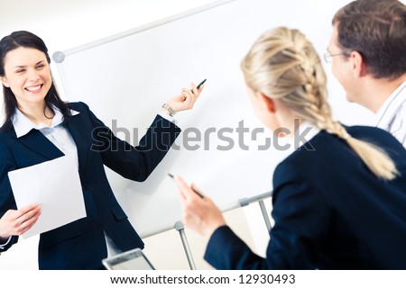 Portrait of successful girl explaining something on whiteboard to her colleagues