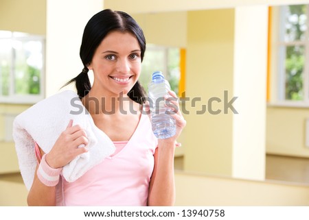 Portrait of sporty girl holding bottle with water in hand in the gym