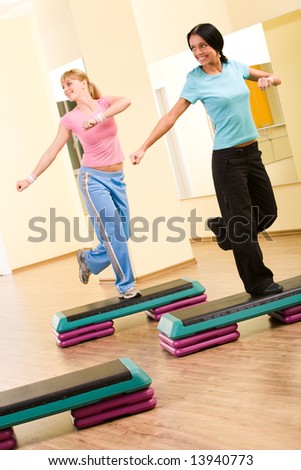 Two sporty women practicing physical exercises standing on one leg and looking to the right