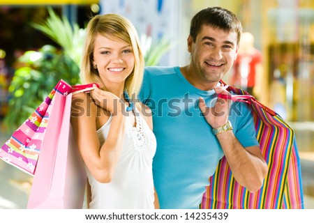Portrait of happy man and woman with shopping bags in the mall