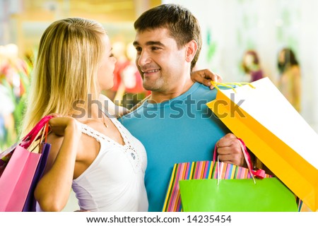 Close-up of man and woman with bags embracing each other in the department store