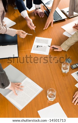 Image of several hands pointing at document at business conference