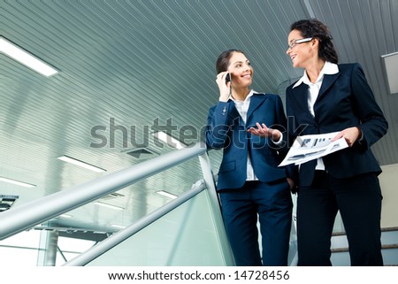 Photo of business ladies walking downstairs and speaking to each other