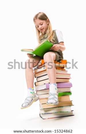 stock photo : Image of schoolgirl sitting on the heap of books and reading one of them