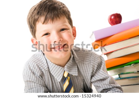 Portrait of joyful kid looking at camera with stack of books and red apple on background