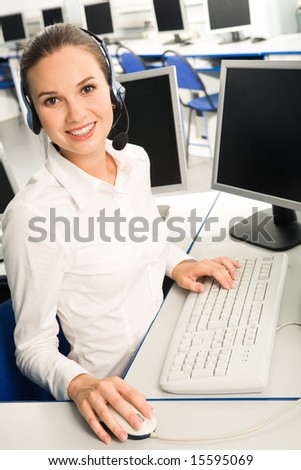 Portrait of attractive consultant with headset sitting at the table in the classroom