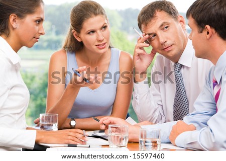 Portrait of serious business partners looking at man explaining new idea and listening to him
