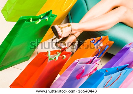 Photo of female legs with colorful shopping bags near by