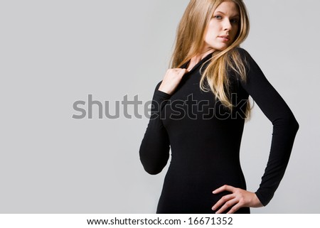 Portrait of seductive lady touching collar of black t-shirt on a grey background