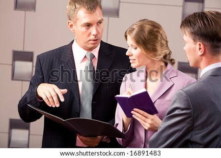 Confident businessman explaining his viewpoint while looking at another man with female between them