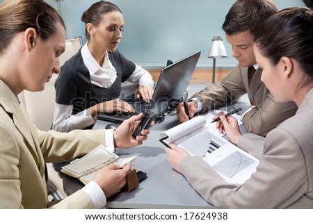 Photo of executive business partners around table interacting with each other