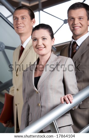 Portrait of smiling business people standing on stairs and looking aside