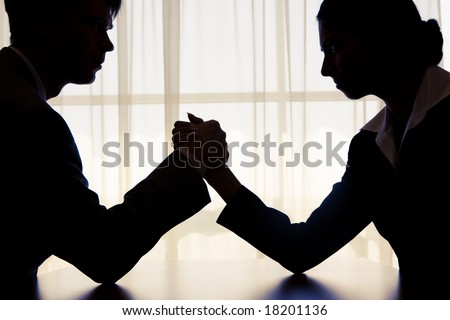 Silhouette of business competitors doing arm wrestling in office