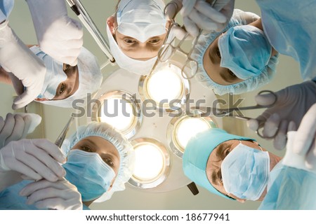 View from below of experienced surgeons with medical tools during operation