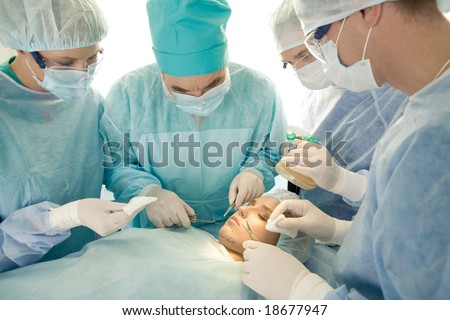 Image of surgeons near operation table with patient on it during operation