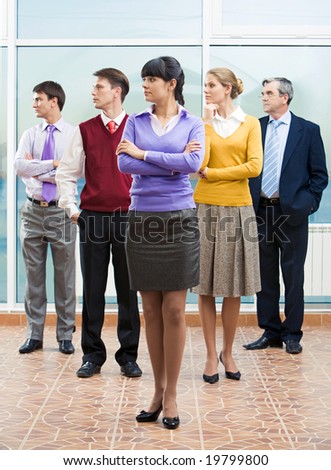 Company of business partners standing and turning their heads aside with serious woman in front