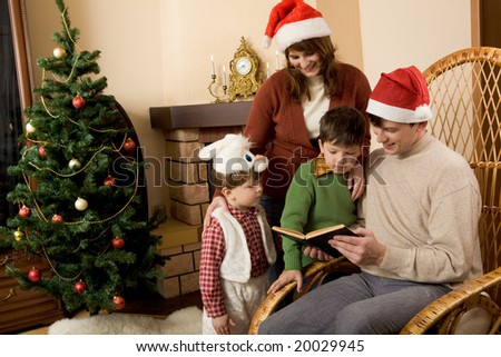 Portrait of family gathered together to read interesting fairy tale with decorated fir tree behind
