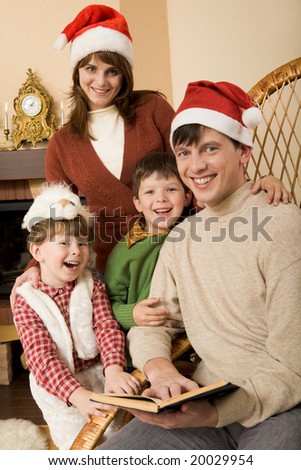 Family gathered together by the fireplace before Christmas and reading a book