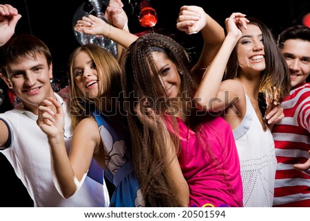 Company of cheerful teens enjoying themselves while dancing at disco