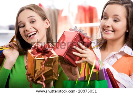 Pretty girls looking at nice presents in their hands and laughing happily