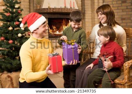Photo of laughing family members with gifts in hands on Christmas night
