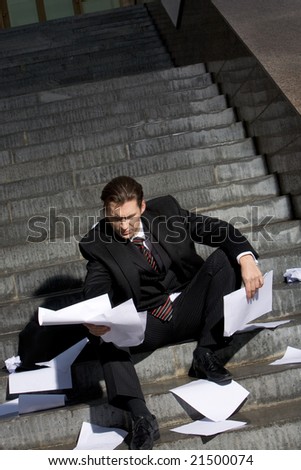 Image of frustrated man sitting with papers in hands and reading them