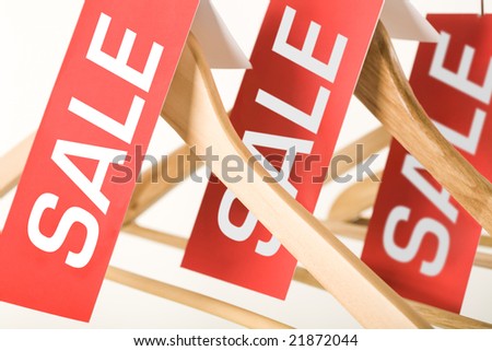 Close-up of red sale labels on wooden hangers in mall or store
