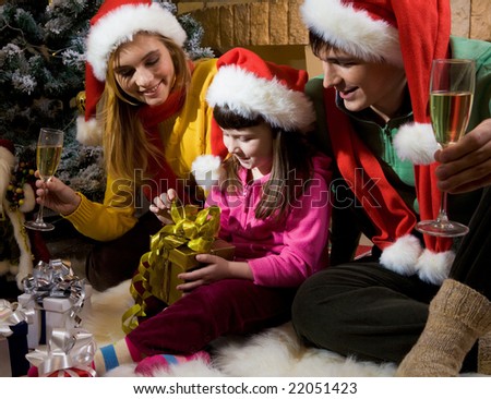 Photo of happy family members looking at nice giftbox in girl?s hands who is going to open it